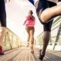 چند زن و مرد در حال دویدن با کفش ورزشی و کتانی ارگونومیک در زمین اسفالت